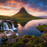 Cascade de Kirkjufellsfoss au premier plan avec la montagne Kirkjufell se reflétant dans le lac sous un ciel flamboyant.