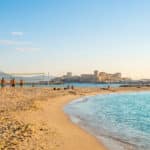 Vue panoramique de la plage des Catalans avec des gens jouant au volley-ball sous un ciel bleu ensoleillé.