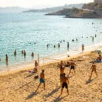 Vue en plongée de la plage du Prophète à Marseille avec des gens qui se baignent et jouent au beach-volley.