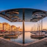 Panorama du Vieux-Port de Marseille avec son abri miroir reflétant les bateaux et les quais au crépuscule.